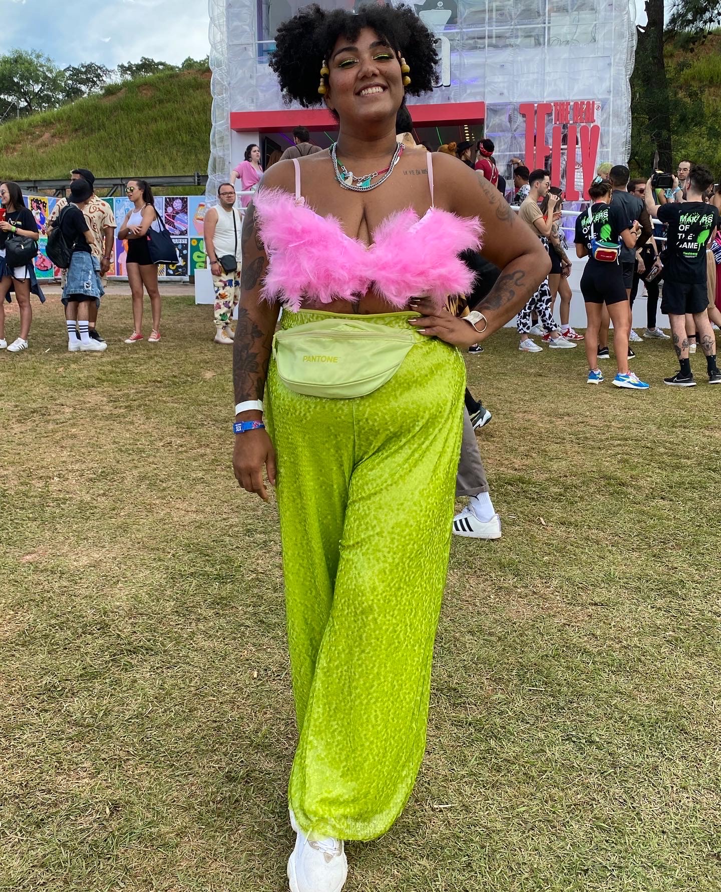 Look da Juliana Santana no Lollapalooza com top rosa de plumas e calça de paetês verde neon