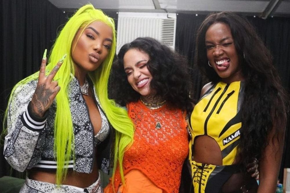 Ludmilla, Kehlani e IZA no Lollapalooza BR; as três estão posando para foto abraçadas nos bastidores do festival