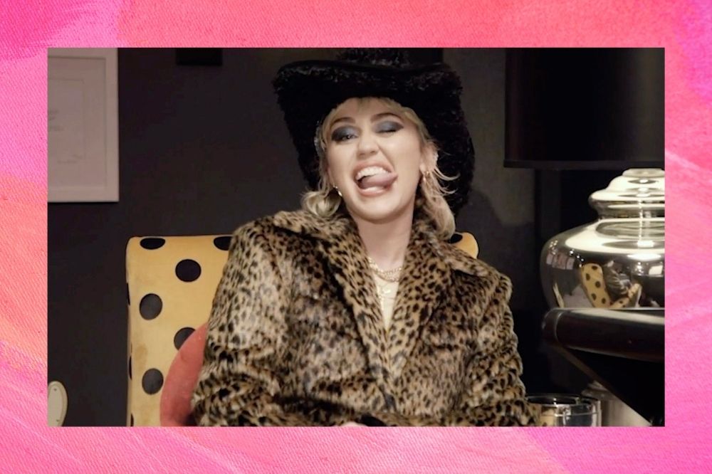 Miley Cyrus sorrindo com a língua de fora e casaco animal print.