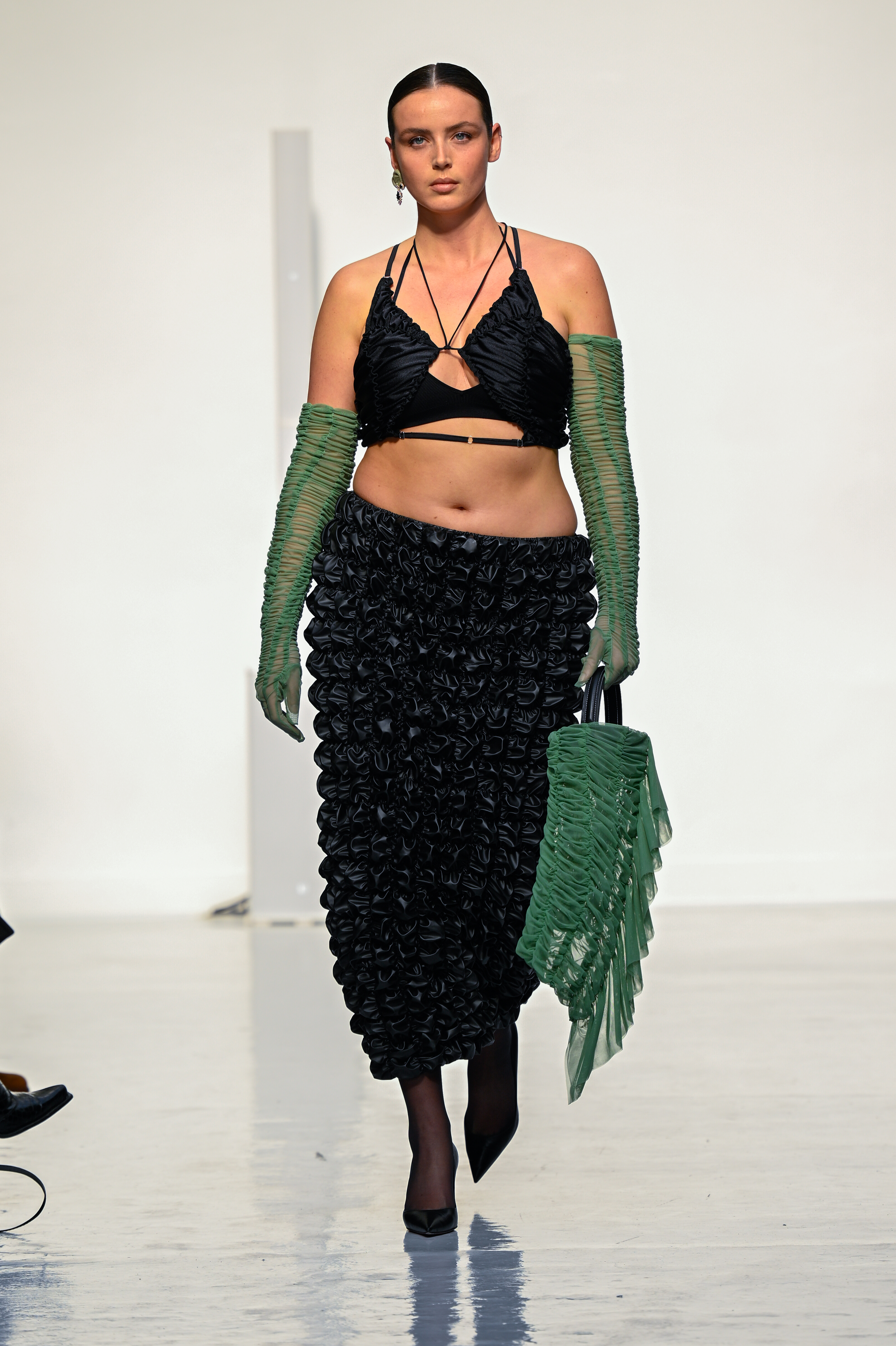 Modelo usando top preto, saia longa preta, luvas verdes e carregando bolsa verde em Desfile de outono-inverno 2022-23 da Ester Manas na semana de moda de Paris