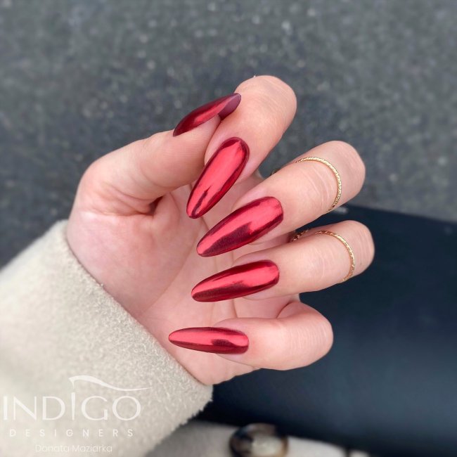 Foto de uma mão com as unhas longas pintadas com esmalte vermelho metalizado.