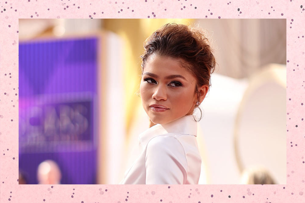 Zendaya no tapete vermelho do Oscar 2022, olhando para o lado. O fundo da montagem é rosa de bolinhas