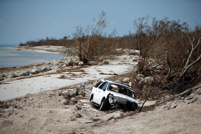 Foto de uma praia deserta, com um carro encalhado na areia, após uma catástrofe climática dizimar a região