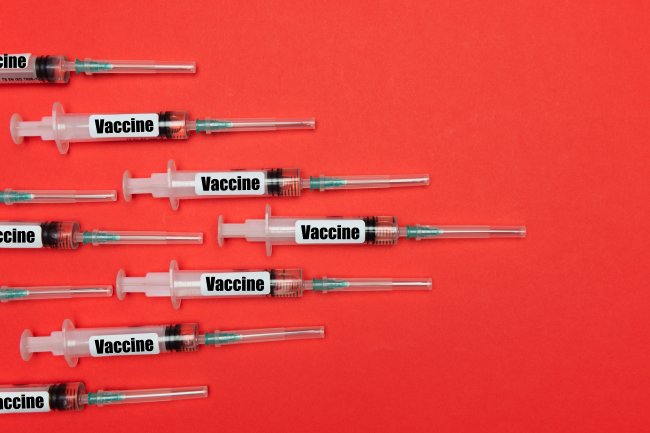 Várias seringas de vacinação deixadas sobre uma mesa vermeha