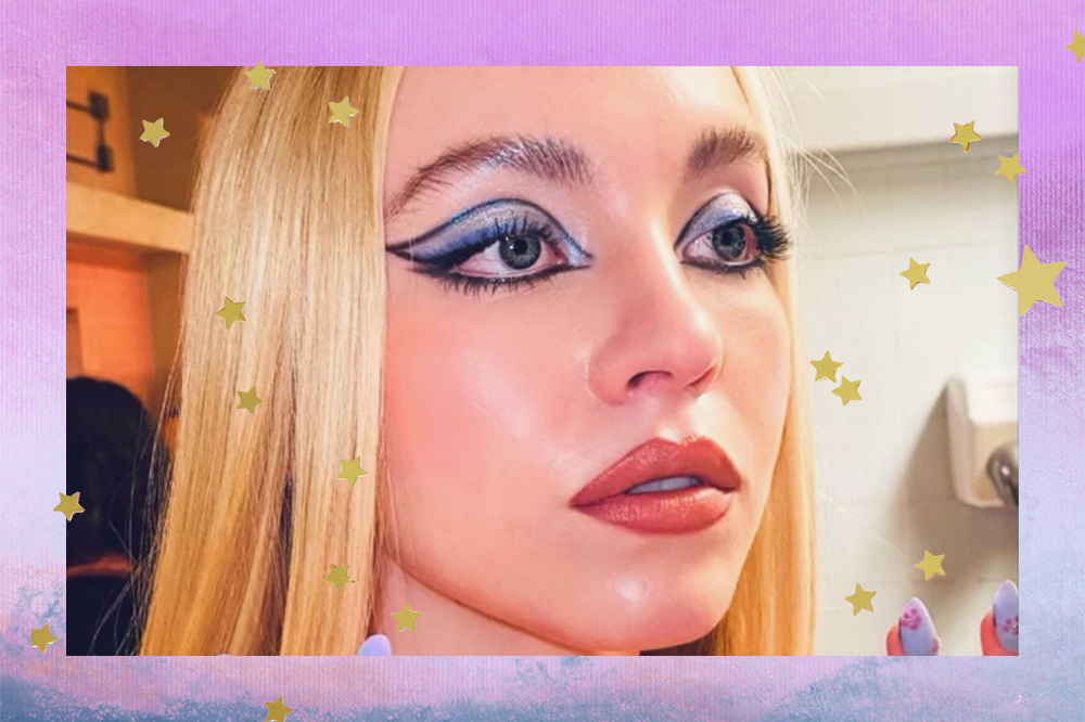 Montagem em fundo degradê azul e lilás com estrelinhas douradas de foto do rosto da Sydney Sweeney usando maquiagem azul nos bastidores da segunda temporada de Euphoria