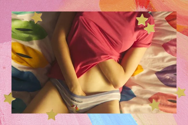 Foto de uma menina branca deitada na cama se masturbando. Ela veste uma camiseta rosa e uma calcinha lilás. Não dá para ver o rosto dela.