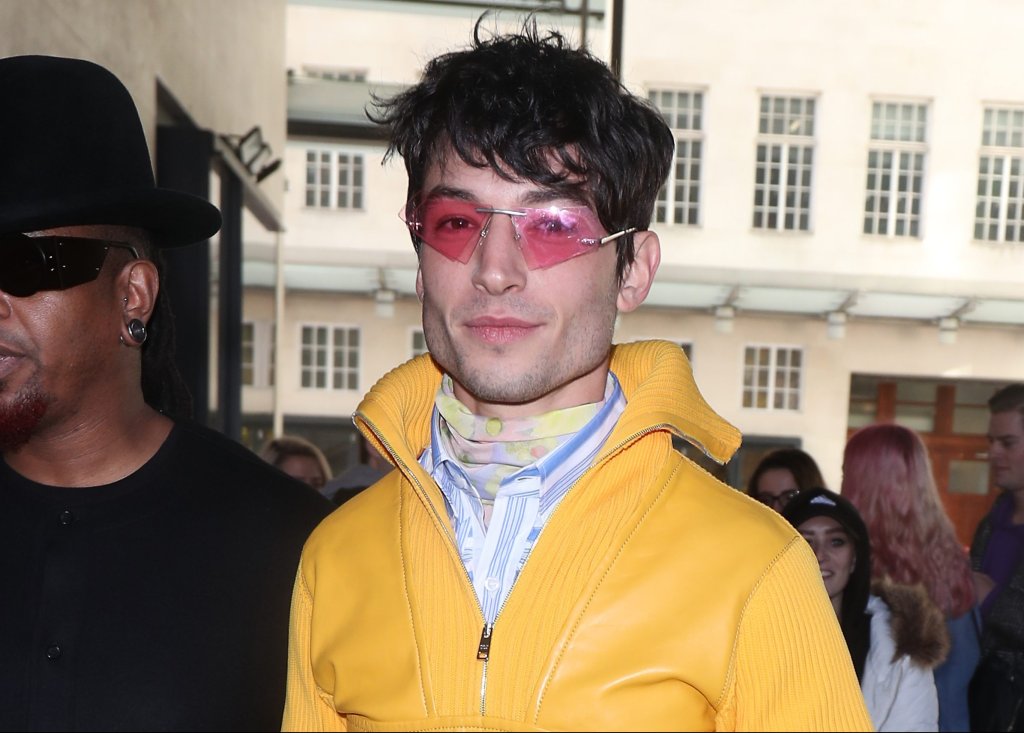 Ezra Miller com jaqueta amarela e óculos rosa