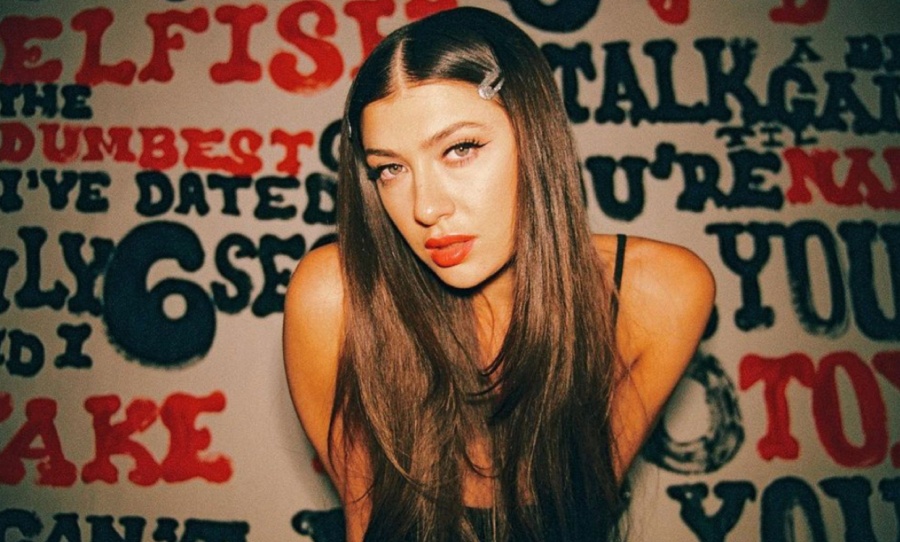 Leah Kate posando com fundo preto, vermelho e branco