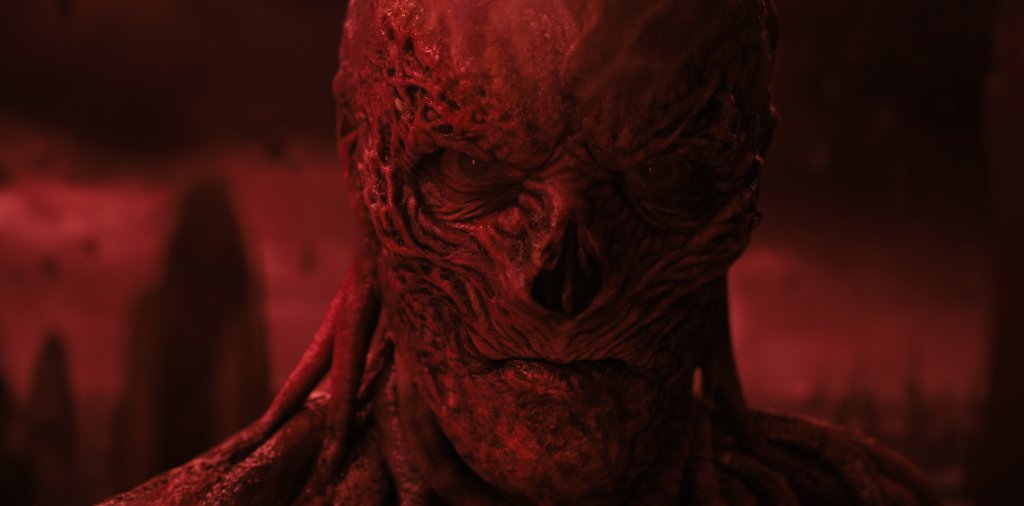 O monstro Vecna em Stranger Things iluminado por uma luz vermelha e com expressão séria/brava