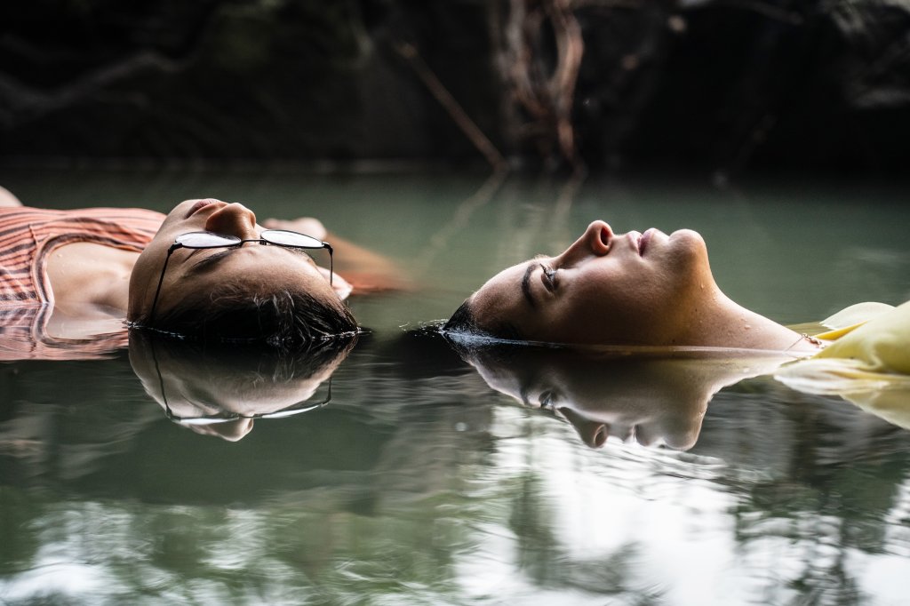 Cena de Você Nem Imagina, da Netflix, com duas meninas na água de um rio/lago olhando para cima