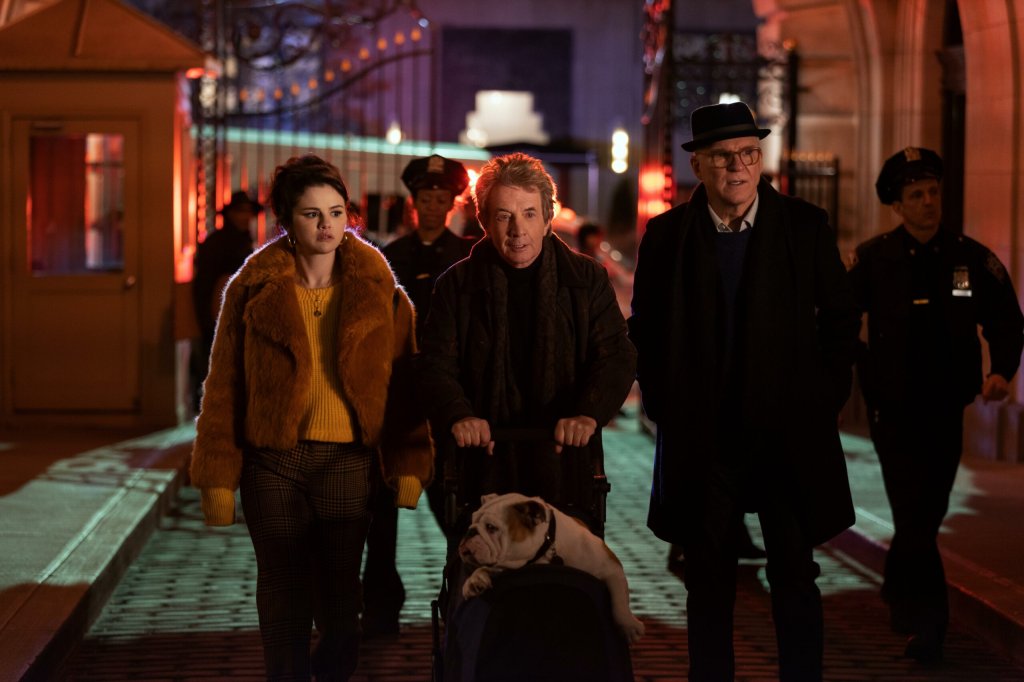 Cena da série Only Murders in the Building com o trio protagonista formado por Selena Gomez, Martin Short e Steve Martin andando na rua durante a noite com um cachorro em um carrinho