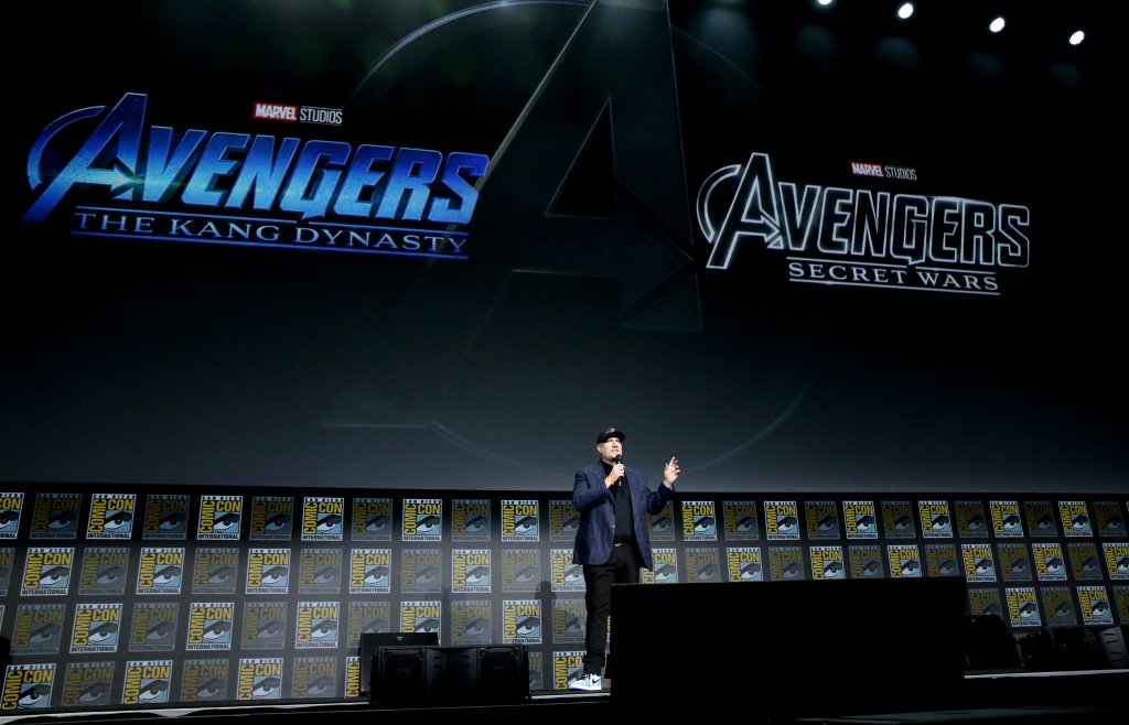 Kevin em palco durante painel da Marvel com telão ao fundo