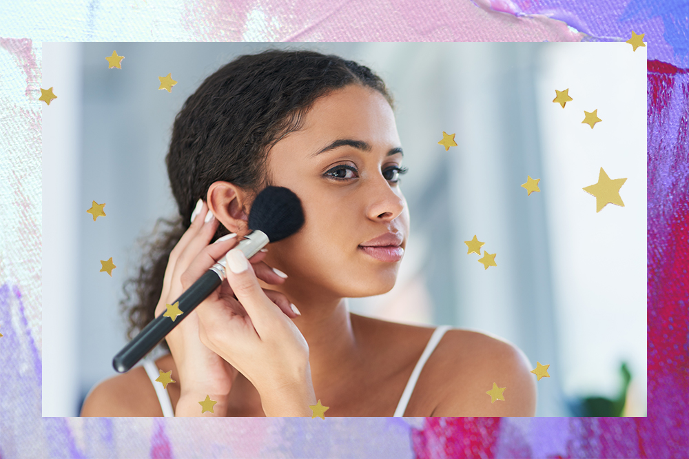 Montagem em fundo lilás, rosa e roxo com estrelinhas douradas com foto de garota em frente a um espelho fazendo maquiagem e aplicando blush nas bochechas com um pincel