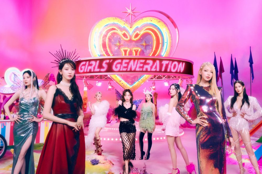 Imagem de divulgação do grupo Girl's Generation; elas estão em um fundo rosa com um coração colorido e brilhante no centro da imagem