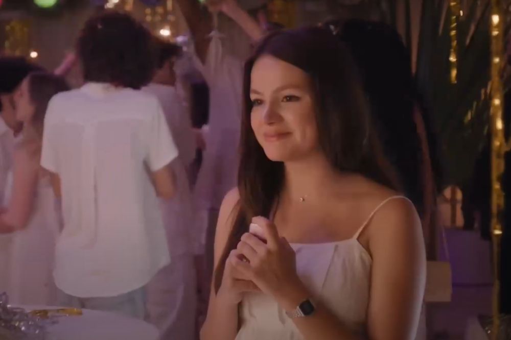 Menina com vestido branco sorrindo em festa e segurando algo nas mãos