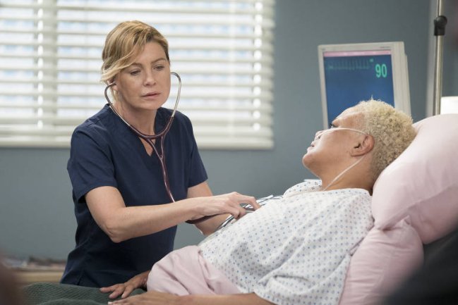 Foto da série Grey's Anatomy. Médica atende paciente e escuta seu coração com a aajuda de aparelhos.