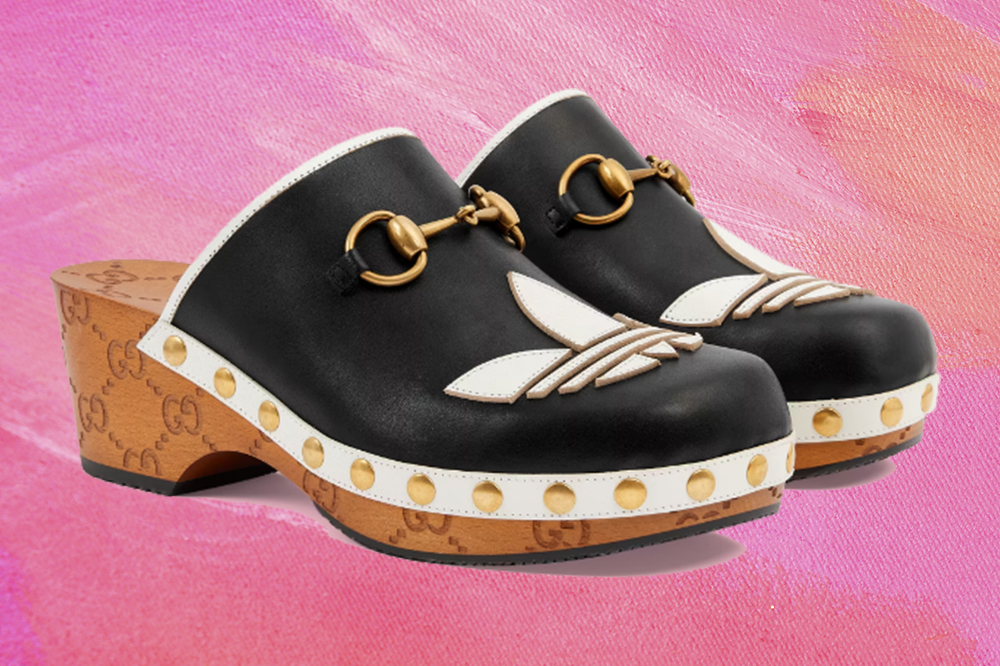 Montagem em fundo rosa de sapato clogs preto e branco com detalhes em dourado da coleção da Adidas em parceria com a Gucci
