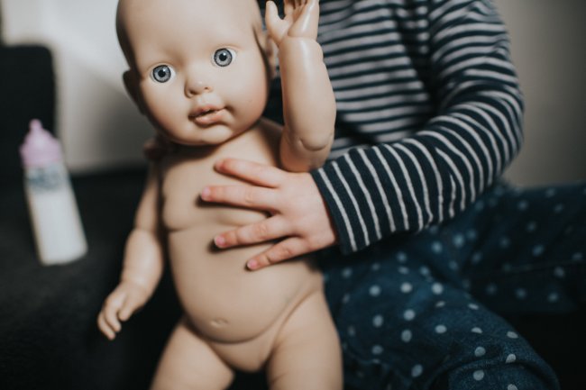 Mão de uma criança segurando um bebê de mentira