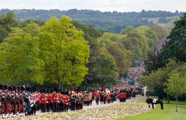Procissão do funeral da Rainha Elizabeth II em direção ao Castelo de Windsor. Há uma multidão de gente assistindo o passar do caixão.