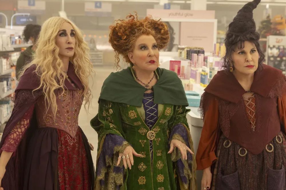 Três bruxas com vestidos longos em farmácia