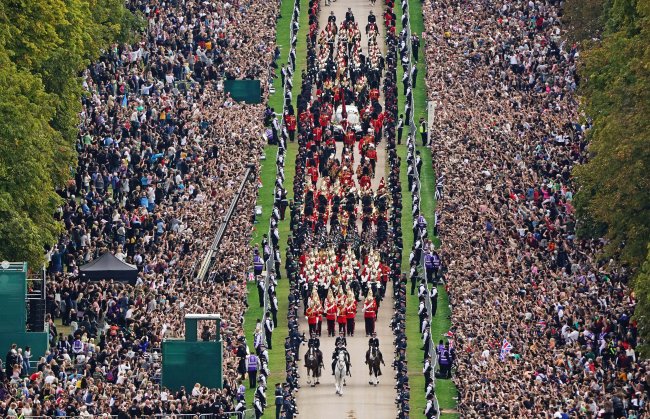 Procissão do funeral da Rainha Elizabeth II em direção ao Castelo de Windsor. Há uma multidão de gente assistindo o passar do caixão.