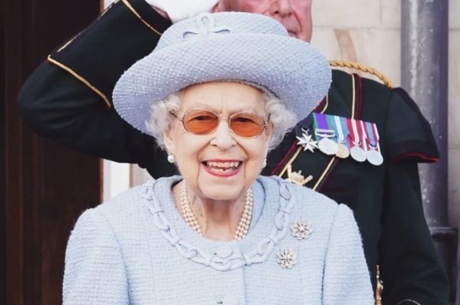 Rainha Elizabeth II com roupa e chapéu azul e óculos de sol