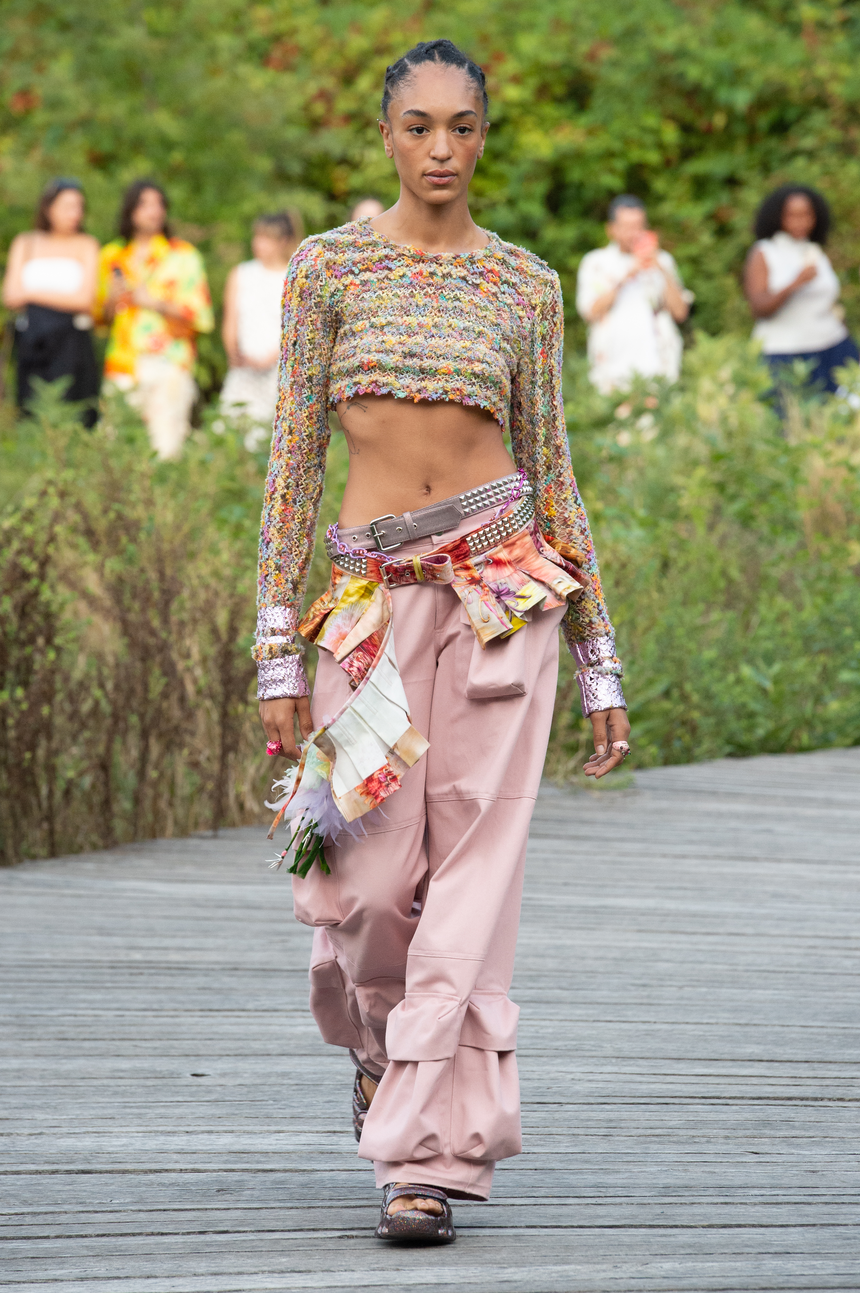 Desfile de primavera-verão 2023 da Collina Strada na semana de moda de Nova York. Modelo usando top cropped colorido, calça rosa de cintura baixa e dois cintos