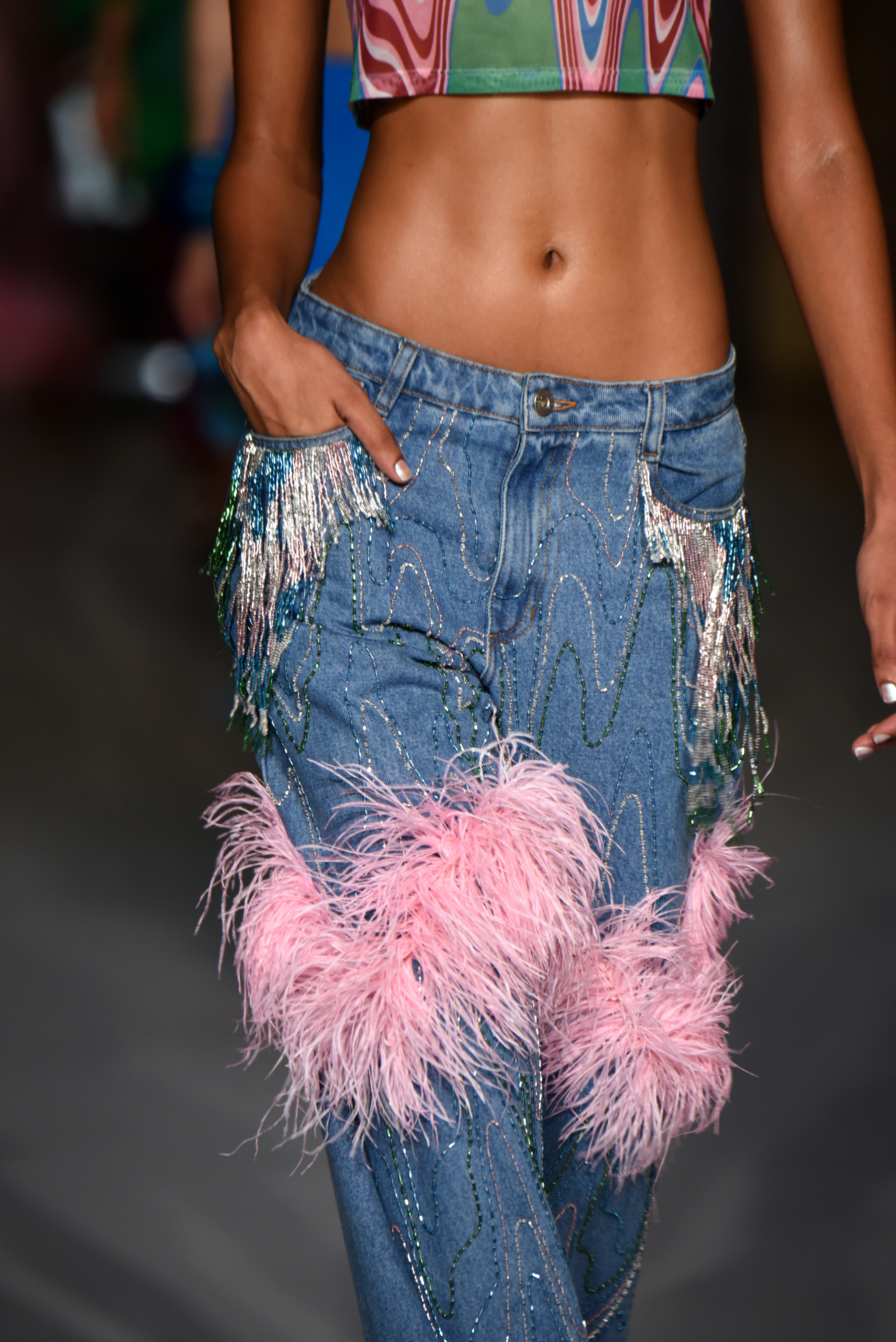 Desfile de primavera-verão 2023 da PatBo na semana de moda de Nova York. Modelo usando calça jeans com aplicações de strass e plumas rosas