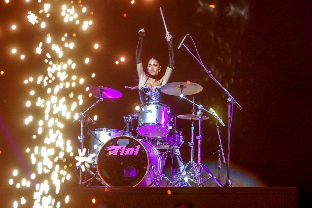 TINI tocando em uma bateria no palco