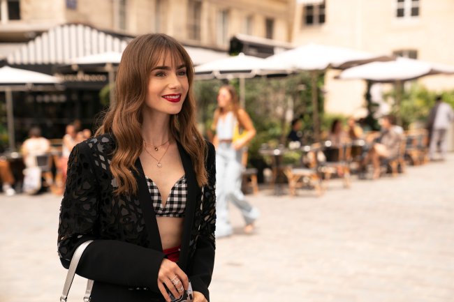 Lily Collins in Emily in Paris;  she's on the street, during the day, standing and smiling