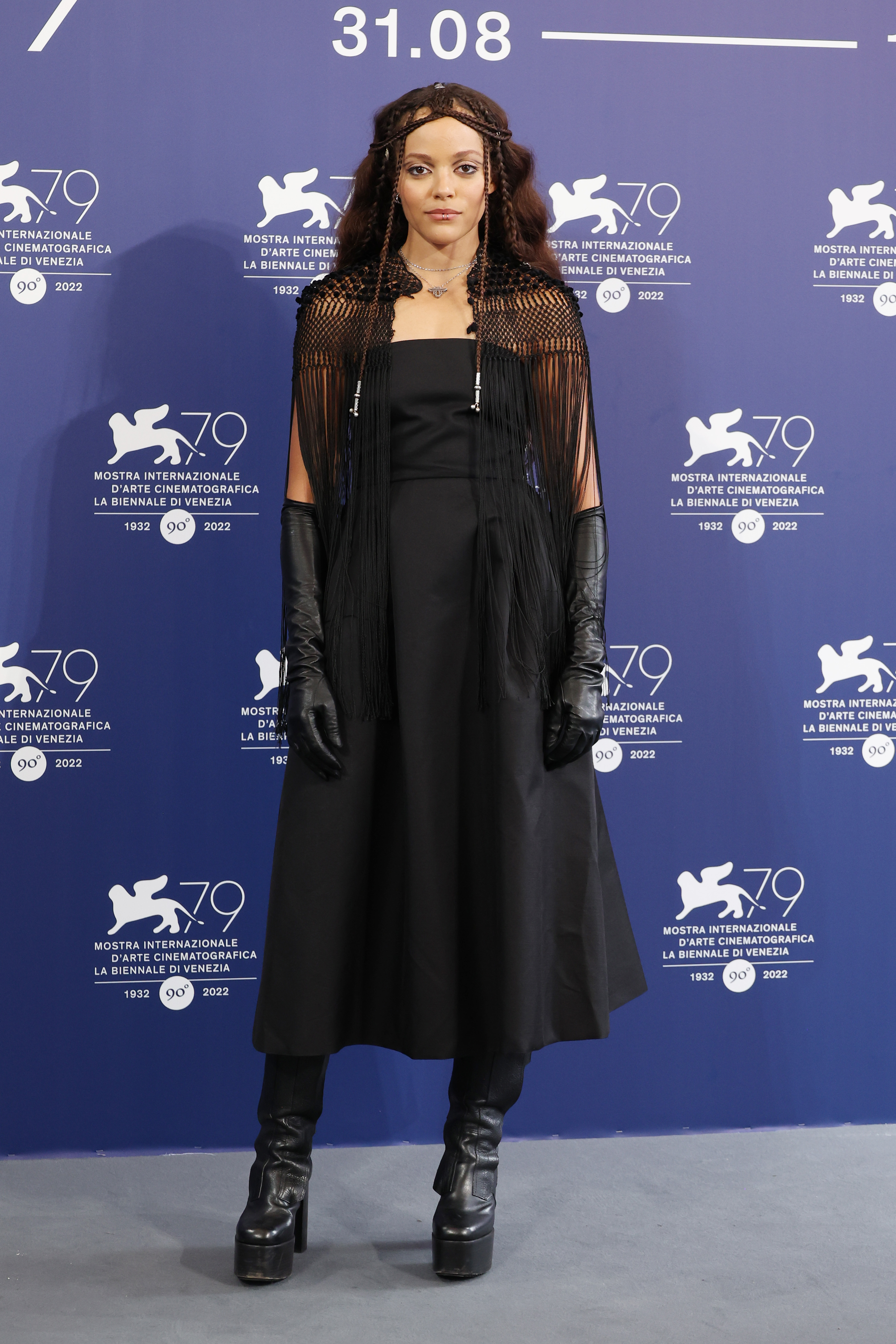 Quintessa Swindell no Festival Internacional de Cinema de Veneza em 2022 usando look todo preto com vestido, luvas e bota