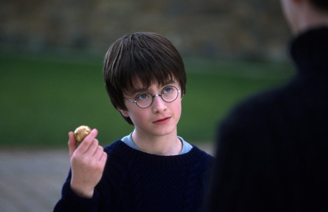 Harry Potter em A Pedra Filosofal, segurando um pomo de ouro