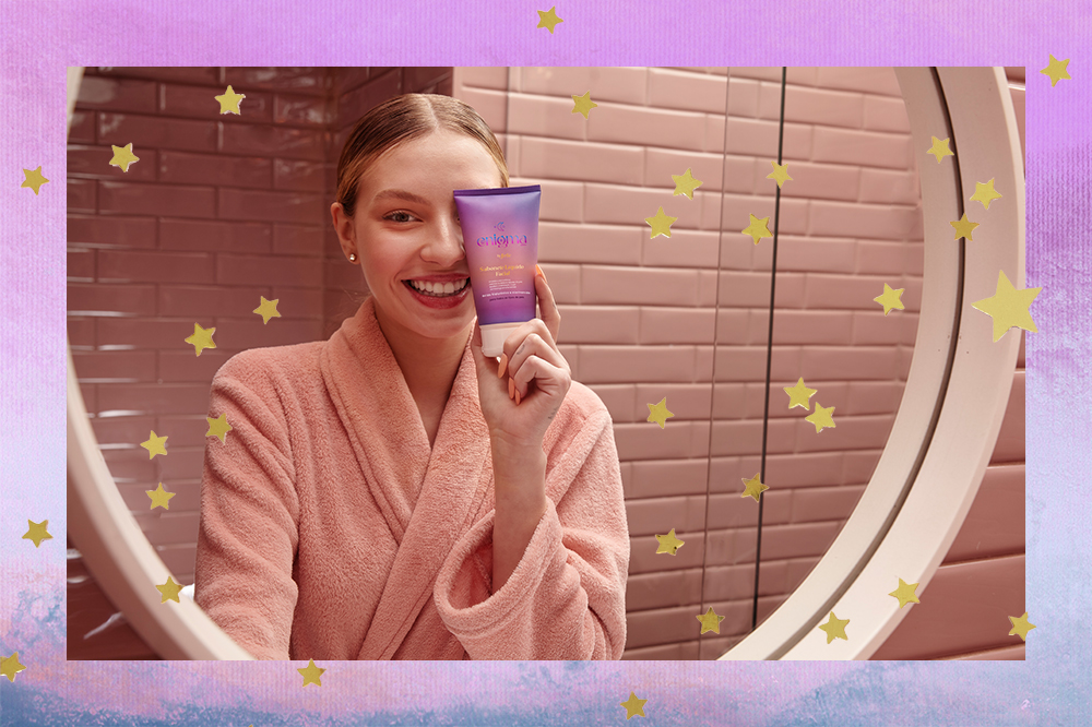 Montagem em fundo lilás e azul com estrelinhas douradas de foto da influenciadora Fefe usando roupão rosa, sorrindo e com seu produto de skincare cobrindo parte do rosto