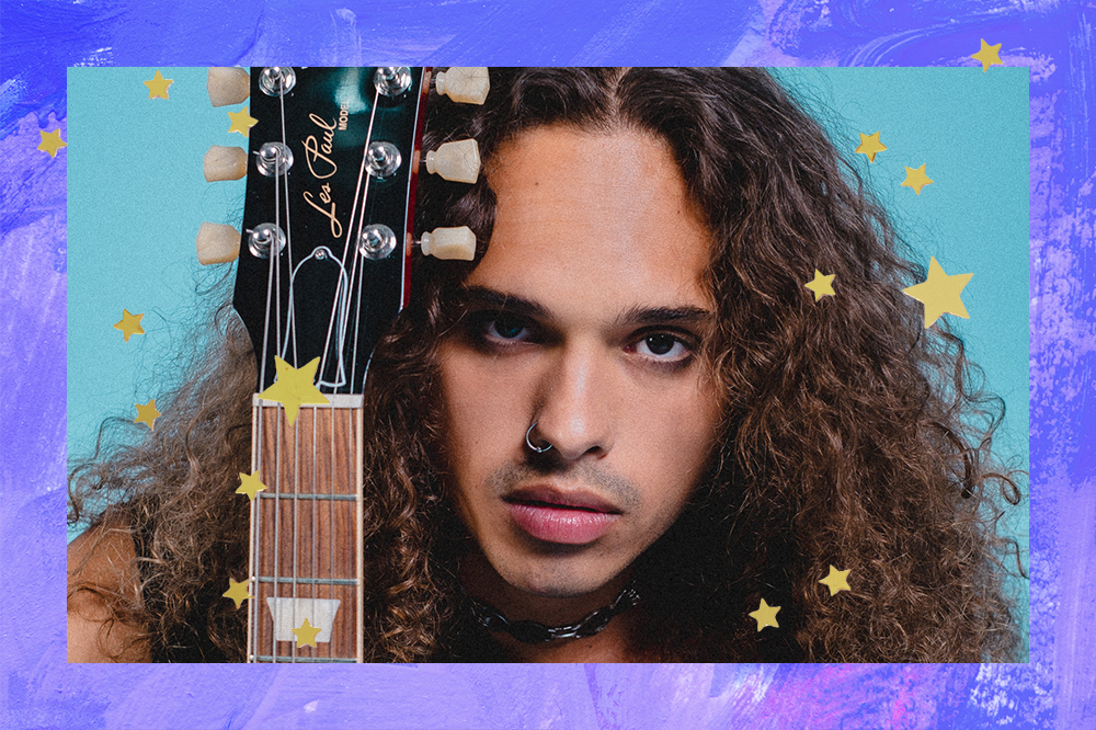 Montagem de foto de Vitão com expressão facial séria segurando uma guitarra ao lado do rosto em fundo azul com estrelinhas douradas