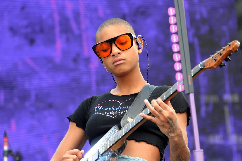 Willow Smith no Audacy Beach Festival em dezembro de 2021 tocando guitarra, usando top cropped preto e minissaia jeans