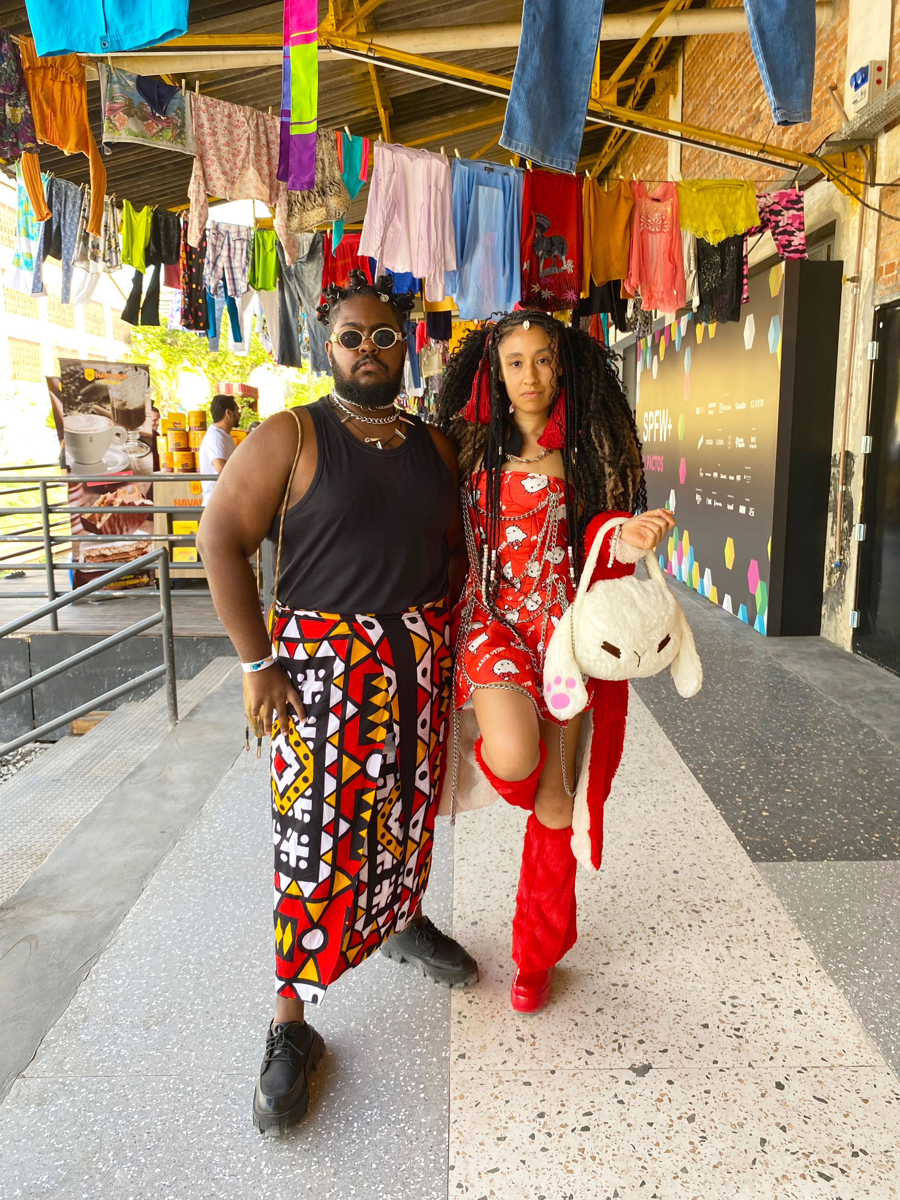 Um homem e uma mulher mostrando seus looks preto e vermelhos no São Paulo Fashion Week