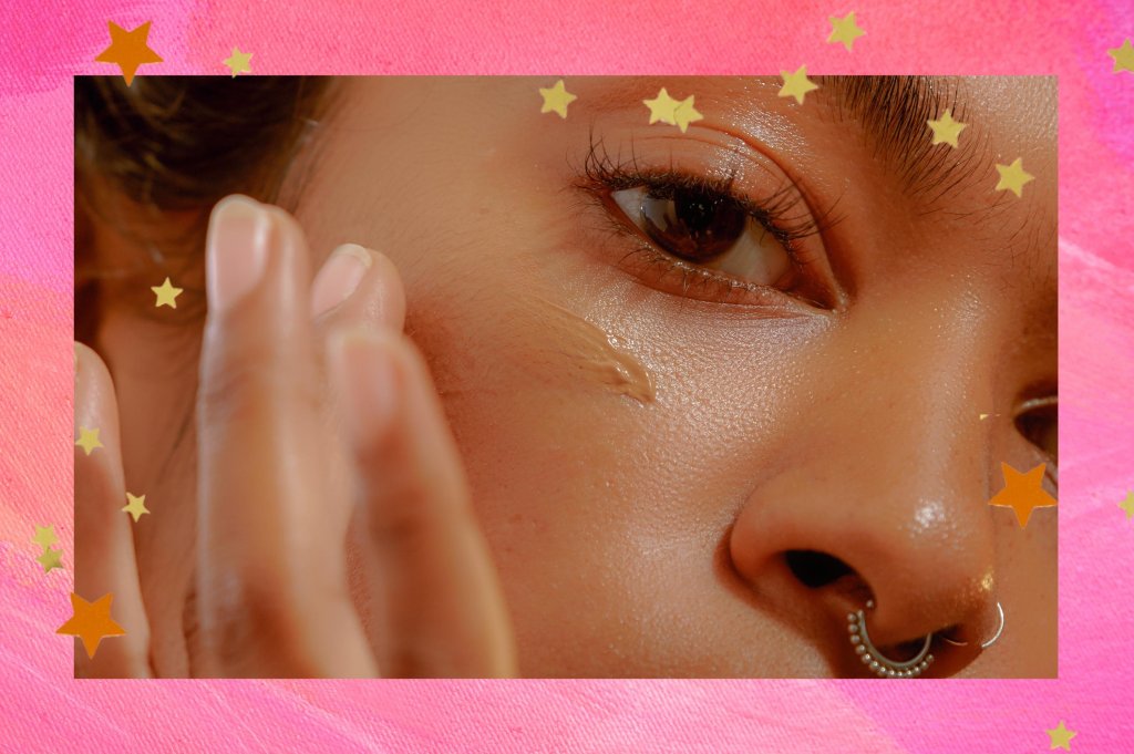 Montagem com o fundo rosa e detalhe de estrelas nas bordas com a foto de um close no rosto de uma mulher aplicando um produto na pele com os dedos.