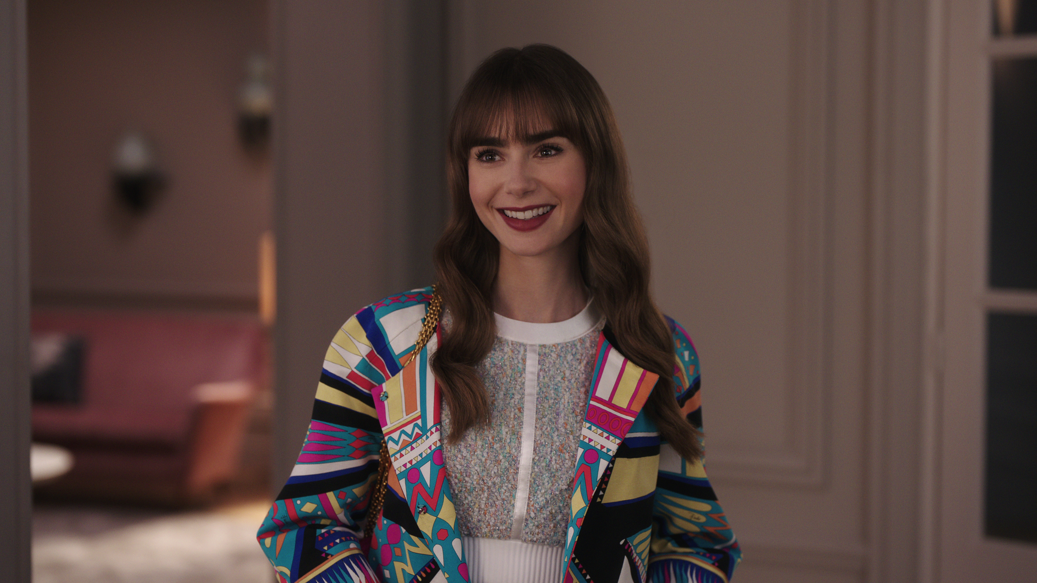 Emily_in_Paris_S3_E9_00_16_38_23RC Lily Collins em cena de Emily in Paris; ela está sorrindo e olhando para frente