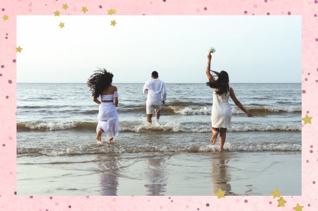 Amigos felizes comemorando o réveillon na praia, correndo para o mar e pulando ondas. Eles usam roupas brancas. Grupo de jovens curtindo e festejando juntos. Conceitos de felicidade, união, juventude e véspera de ano novo.