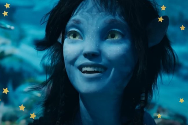 avatar Kiri, personagem de Avatar: O Caminho da Água, sorrindo com olhar de admiração enquanto está debaixo d'água em cena do filme