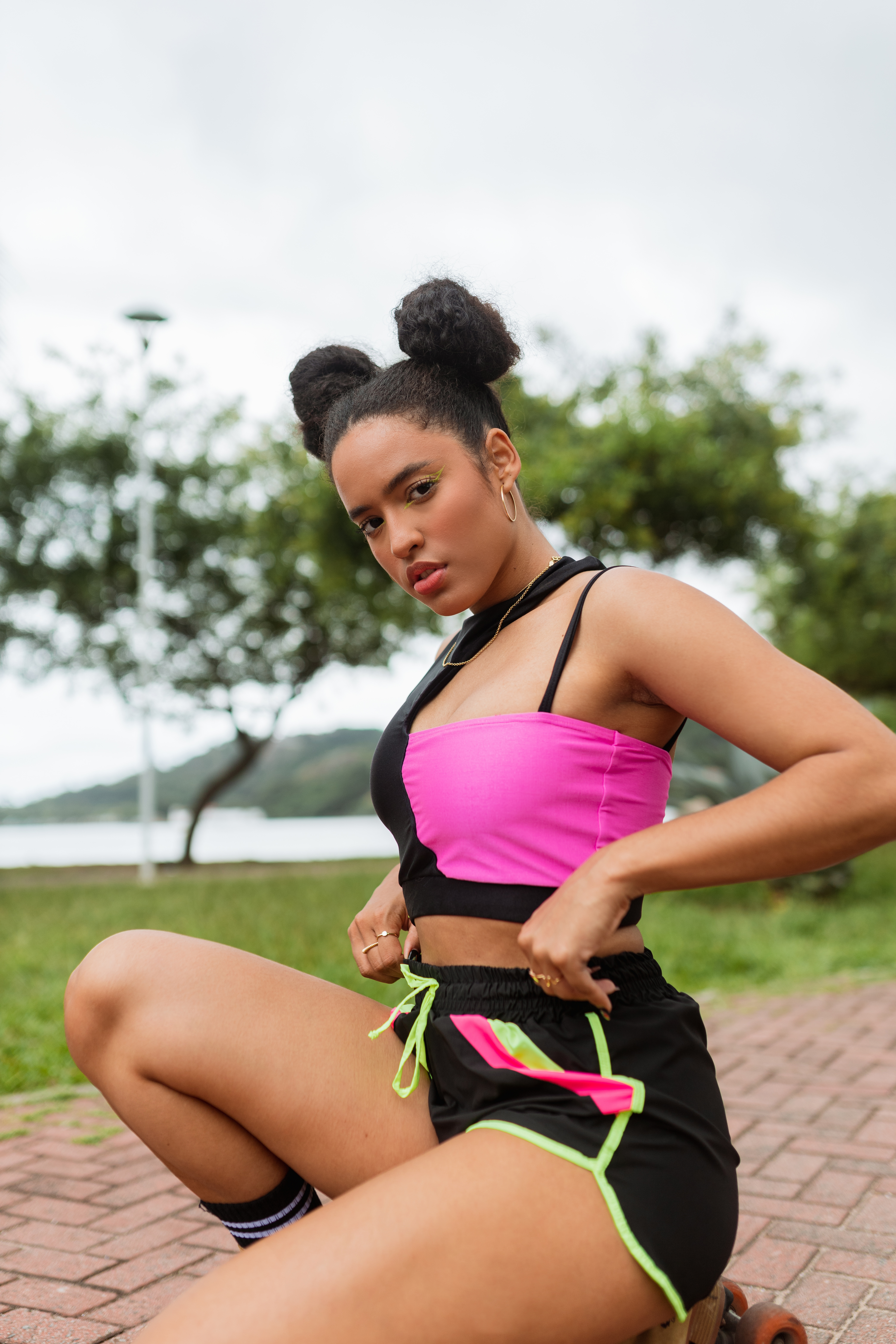 Modelo usando top e short preto com rosa e verde neon da Coleção de roupas da CAPRICHO com a Agua Azul