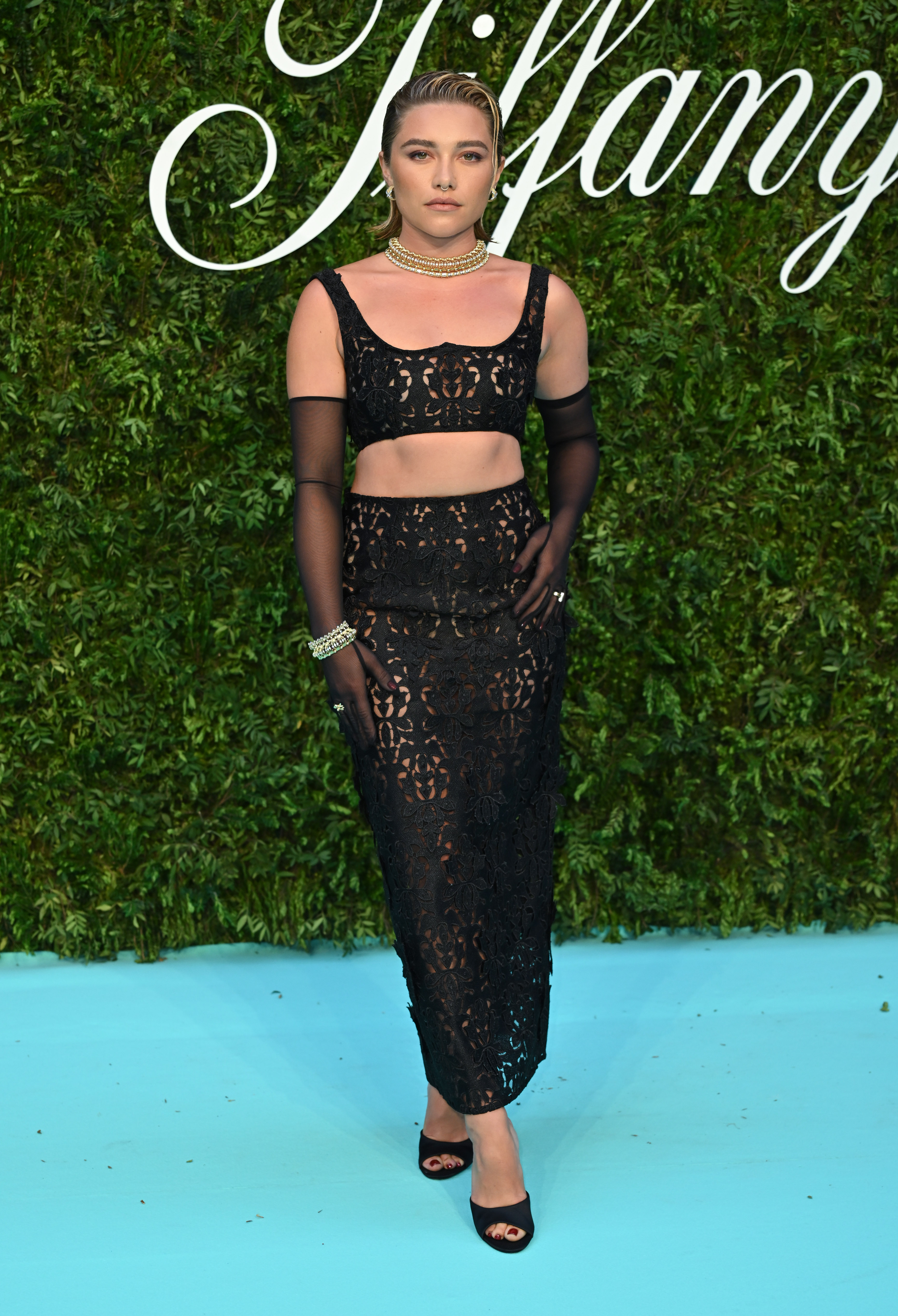 Tiffany & Co. “Vision & Virtuosity” Brand Exhibition Opening Gala -Arrivals Florence Pughem evento da Tiffany & Co. em Londres, em junho de 2022 usando top cropped e saia preta de renda com transparência e luvas transparentes