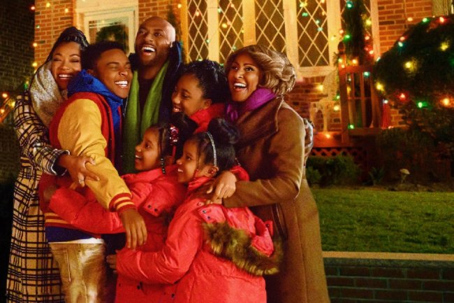 Cena do filme O Natal Está no Ar. Uma família negra se abraça em frente a uma casa decorada