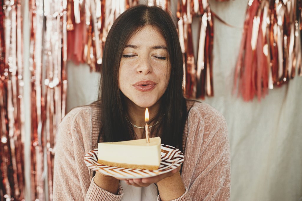 Garota soprando vela de um pedaço de bolo de aniversário