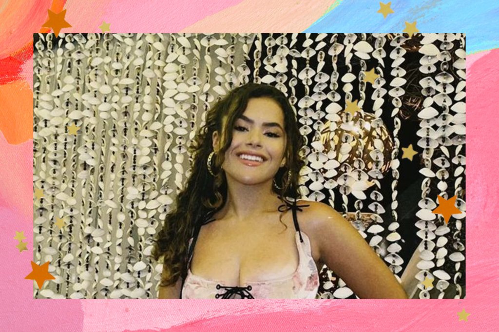 Montagem com o fundo rosa em tons de rosa e azul com detalhes de estrelas nas bordas com a foto da Maisa no centro. Na foto ela está com o cabelo meio preso, maquiagem simples e look com corset com estampa de flores. Ela olha para a câmera e sorri.