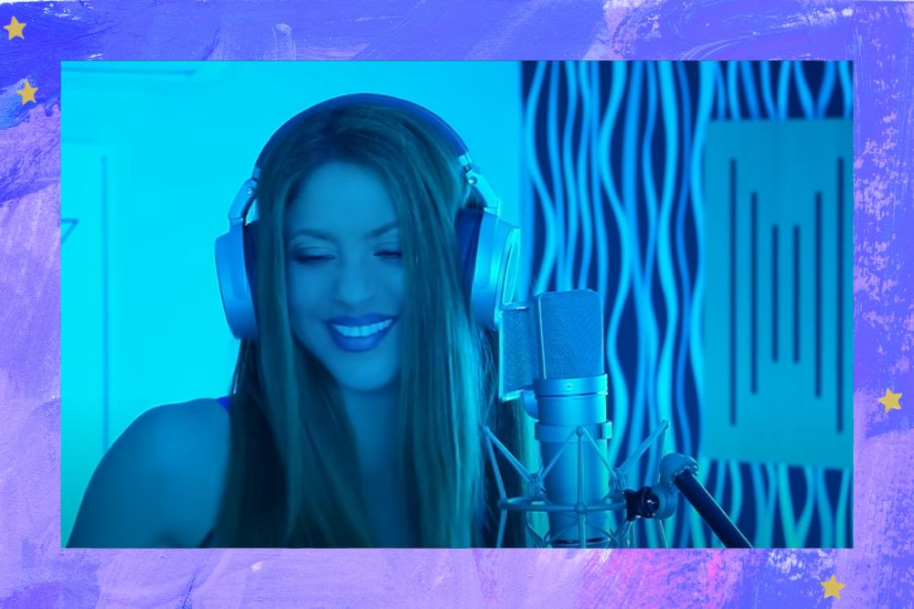Shakira sorrindo enquanto usa fones de ouvido e canta com um microfone na sua frente, a iluminação do ambiente é azul; a margem é uma textura nas cores roxo, lilás e branco