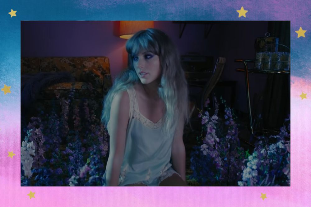 Taylor Swift no clipe de Lavender Haze; ela está sentada no chão de uma sala de estar olhando para o lado rodeada por lavandas; a margem é uma textura em tons de azul e rosa com estrelas amarelas como decoração