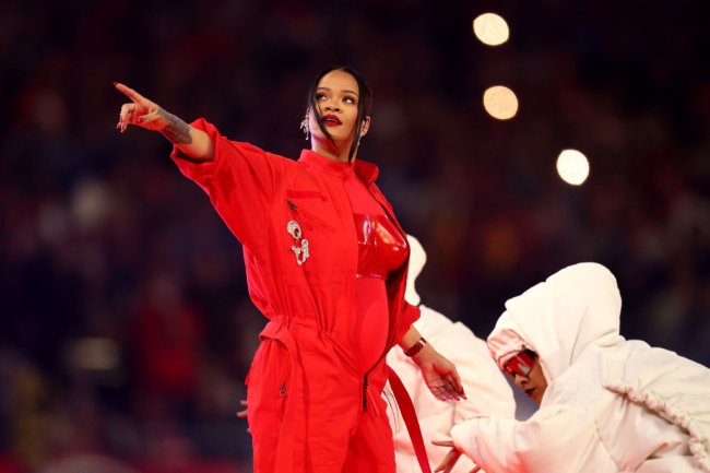 Apresentação de Rihanna no show do intervalo do Super Bowl; ela veste uma roupa vermelha aponta enquanto dançarinos estão em volta dela usando roupas brancas