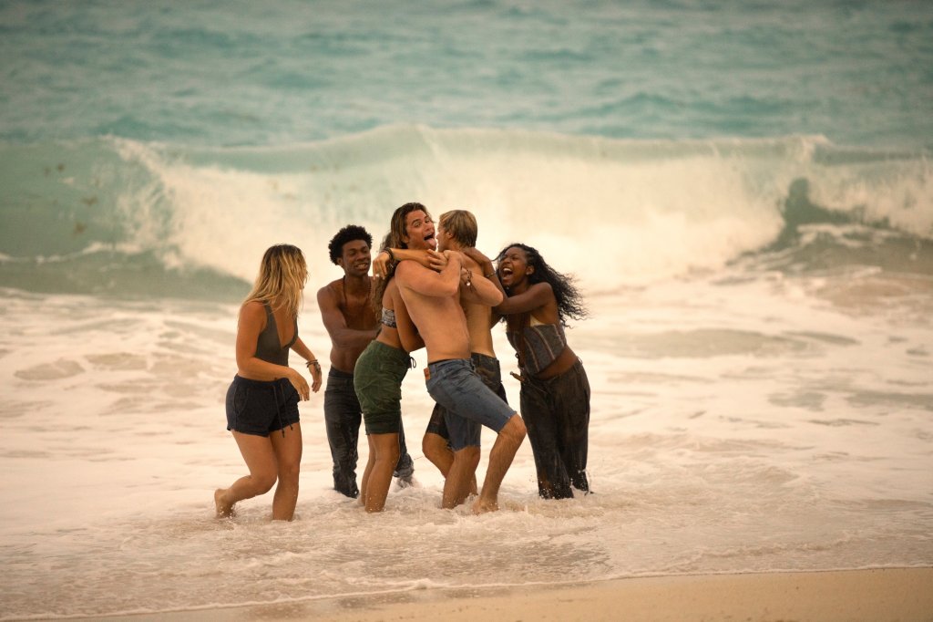 Personagens de Outer Banks rindo e se abraçando no mar
