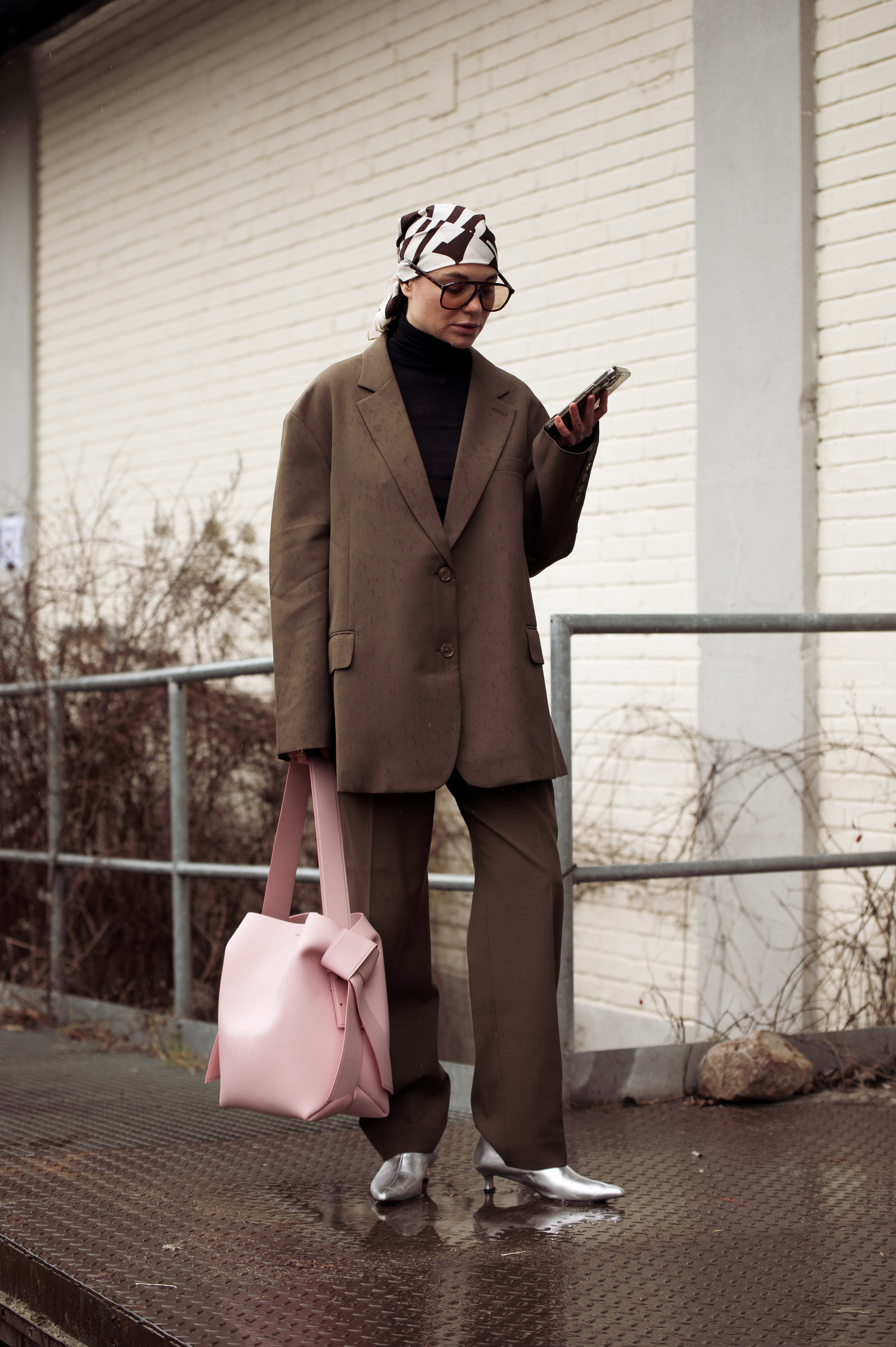 Street Style – Day 2 – Copenhagen Fashion Week Autumn/Winter 2023 Alice Fetisova na semana de moda de Copenhagen usando conjuntinho marrom de alfaiataria, bolsa rosa e lenço estampado no cabelo